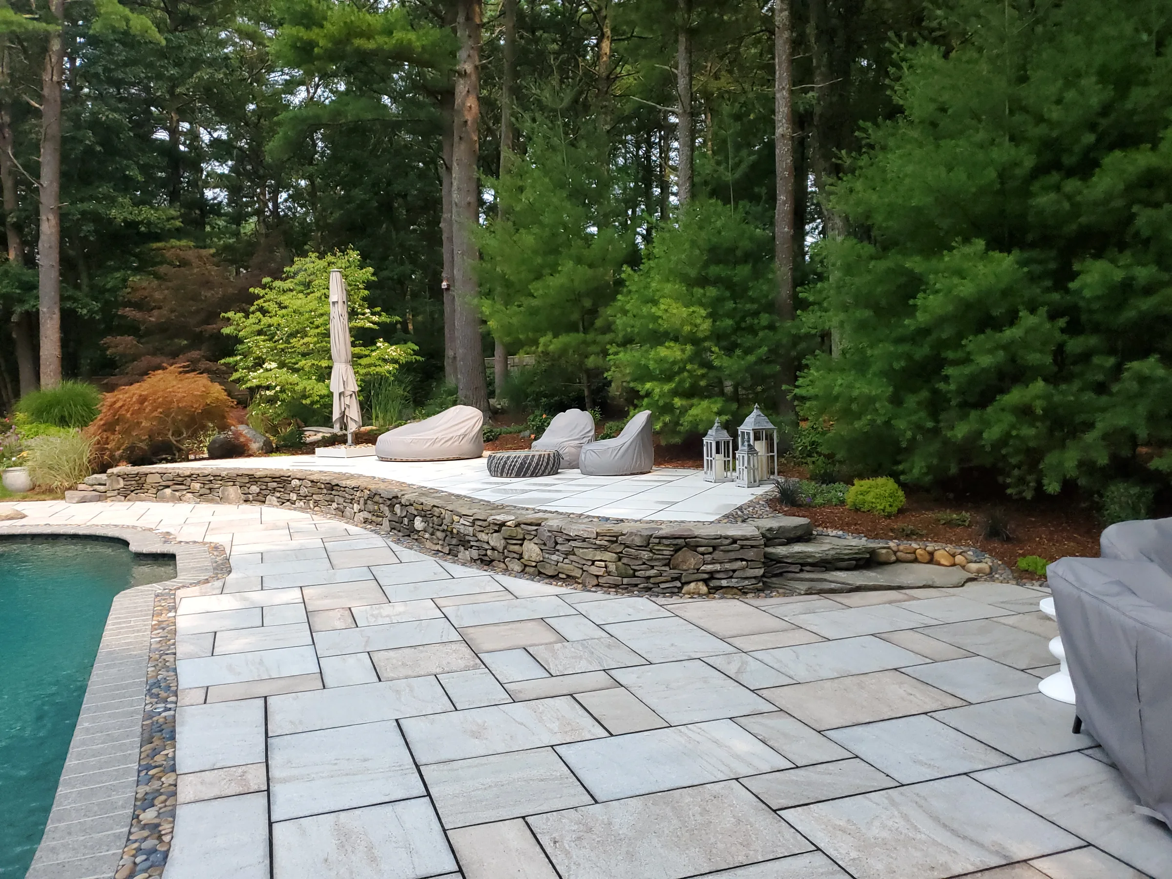 Large pool terrace with layered stone walls and lounge areas