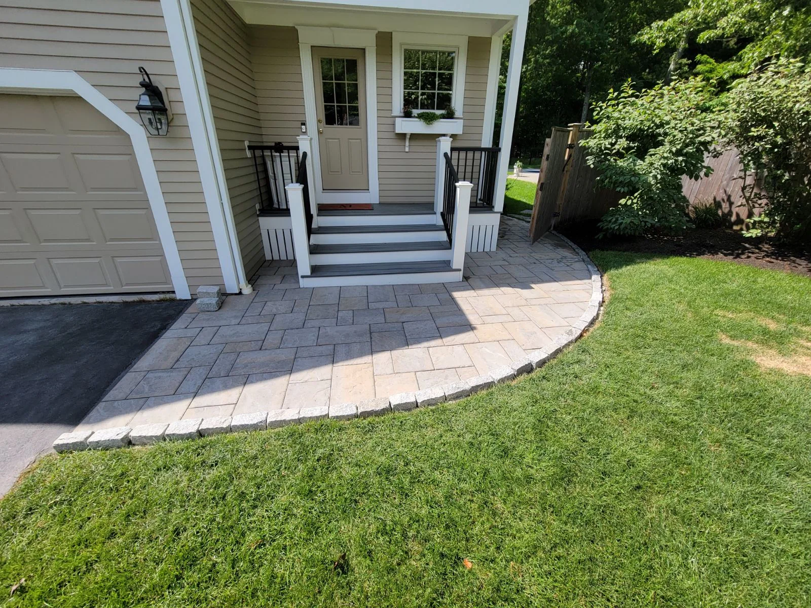 Curving paver walk bordered by dark mulch and clipped shrubs