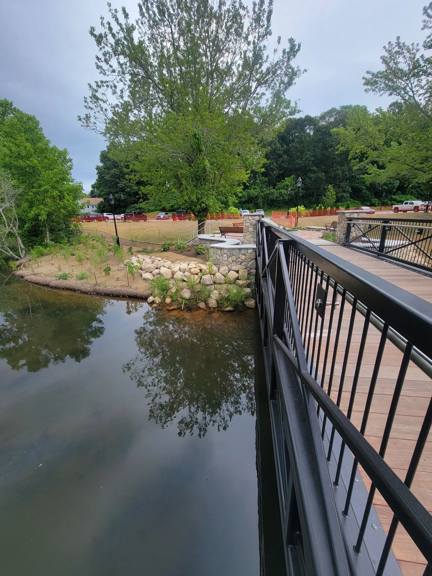 Railed walkway following the edge of a landscaped pond