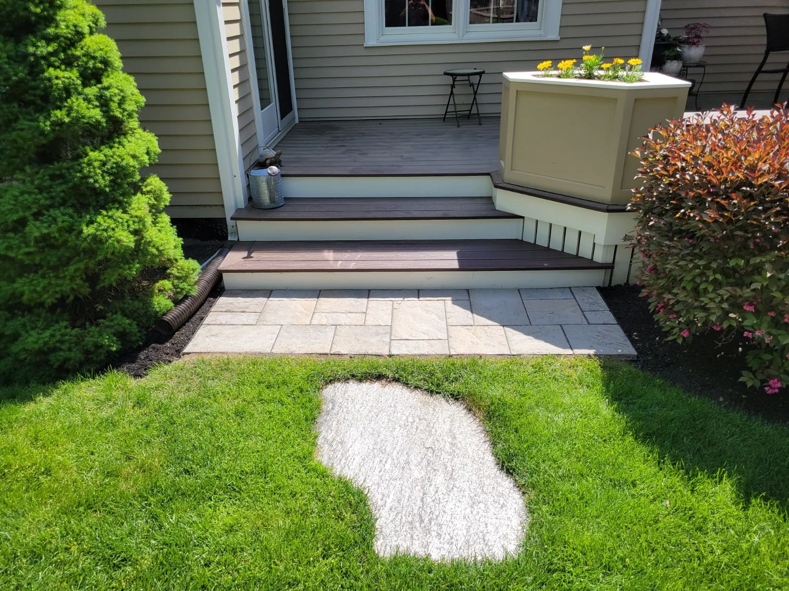 Paver landing and front porch steps beside a lawn with a white gravel inset