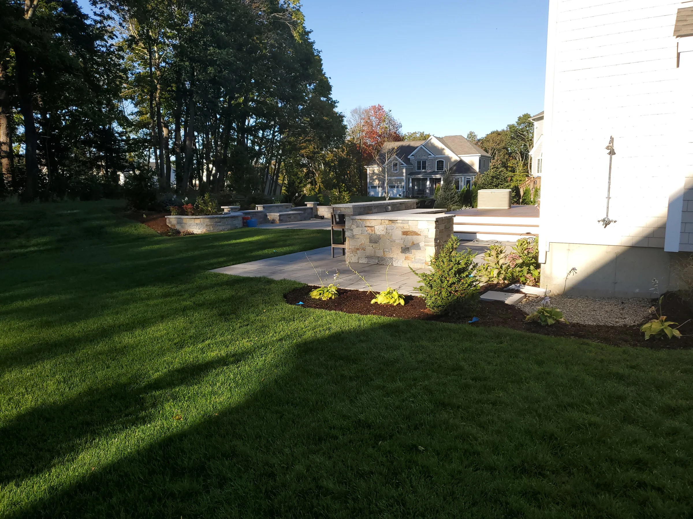 Finished lawn and stone patio beside a light-colored home