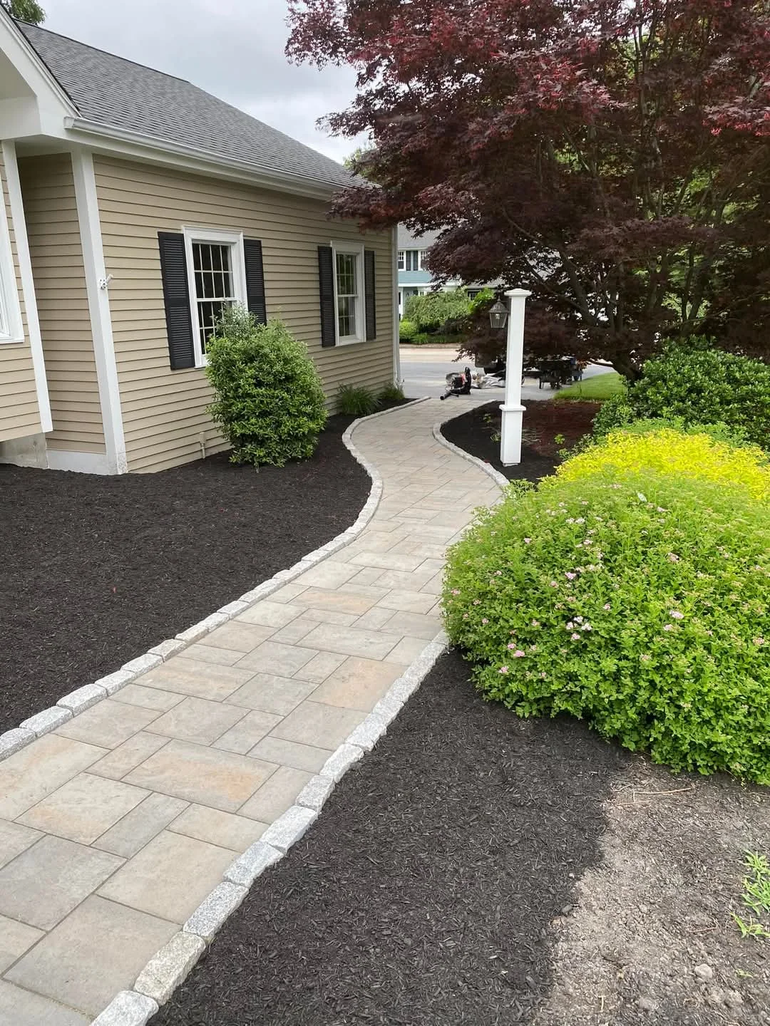 Paver walkway and low landscape wall beside a home