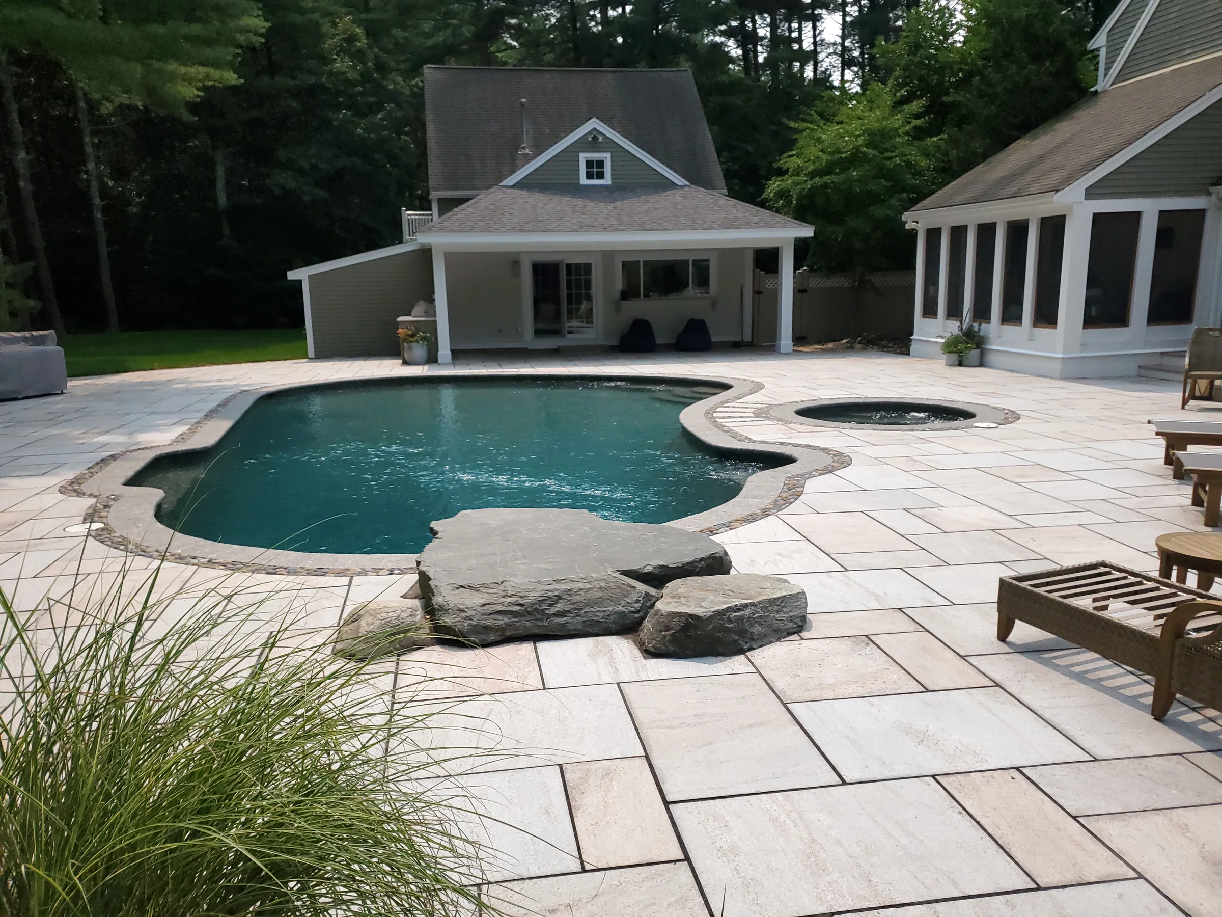 Wide view of a pool, spa and surrounding geometric paver terrace