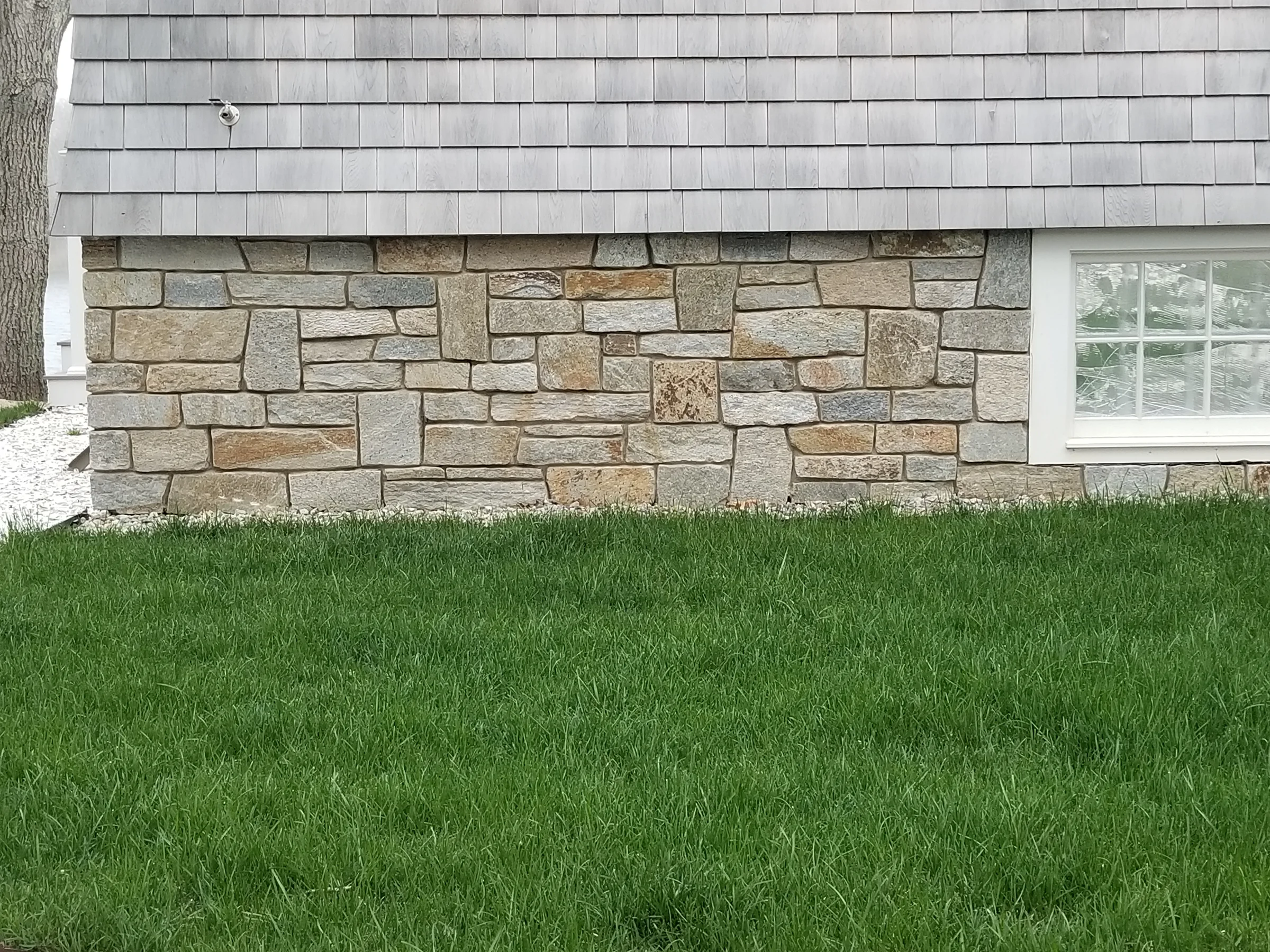 Natural stone veneer wrapping the base of a shingled building