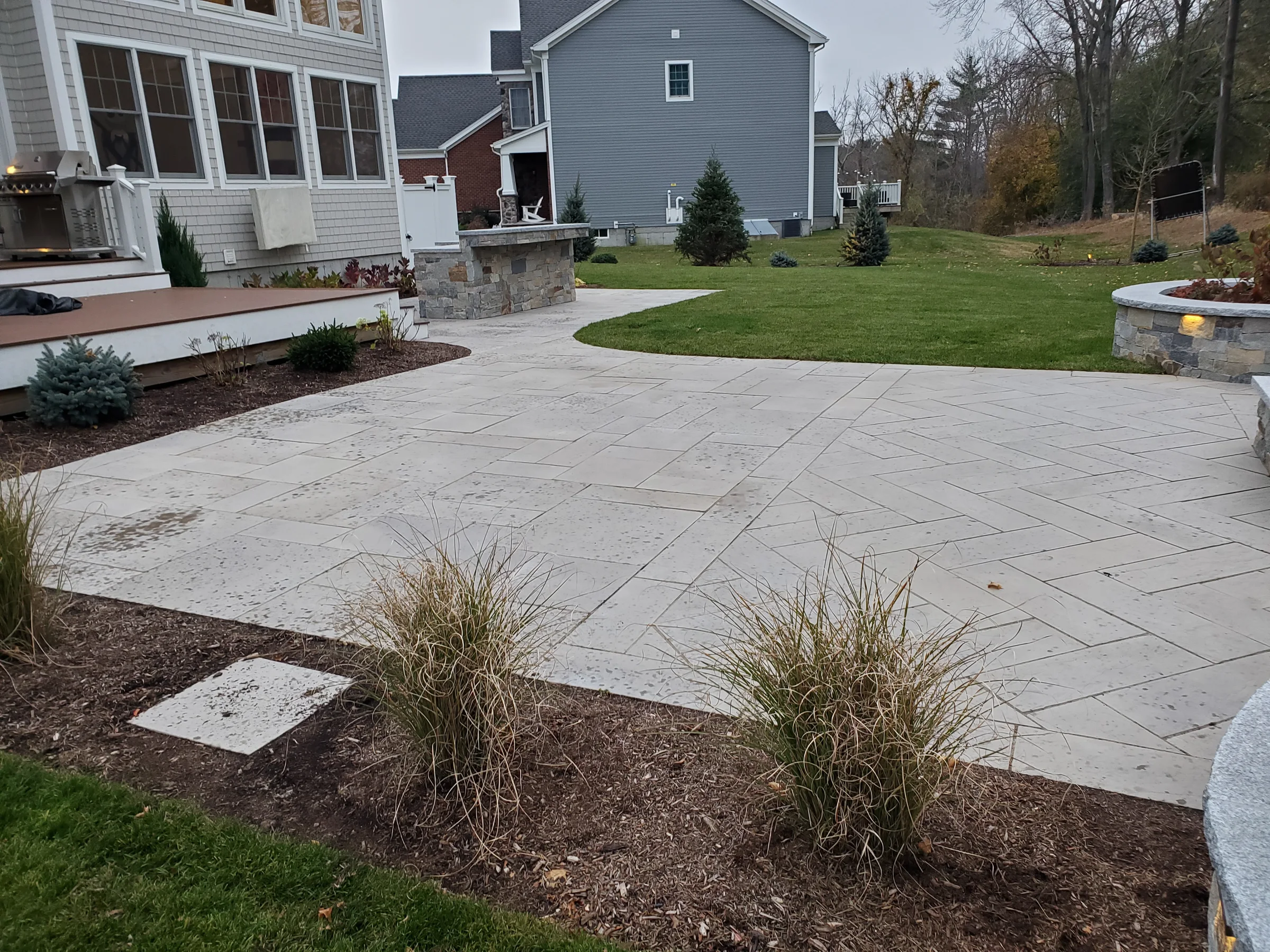 Broad geometric patio with lawn and low stone features