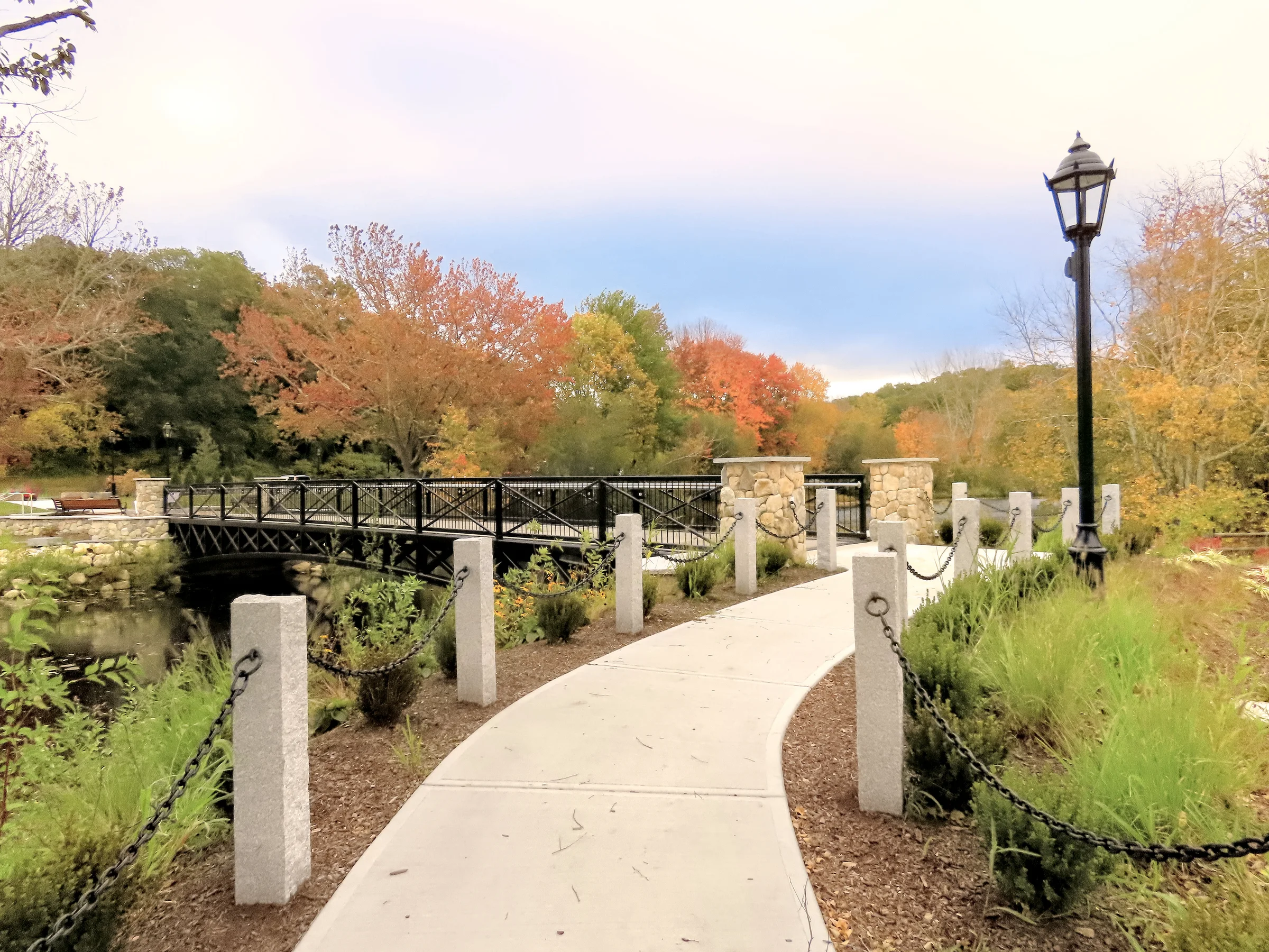 Curving public walkway with railings, stone piers and fall plantings