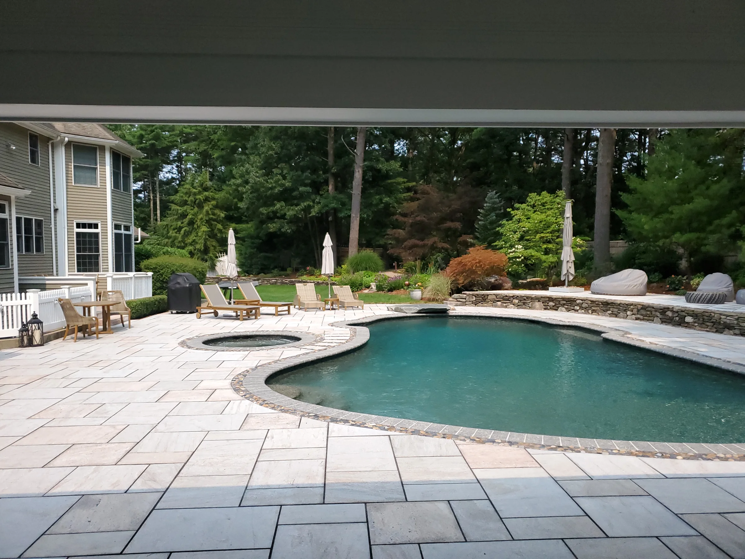 Finished pool patio with generous seating and pale stone paving
