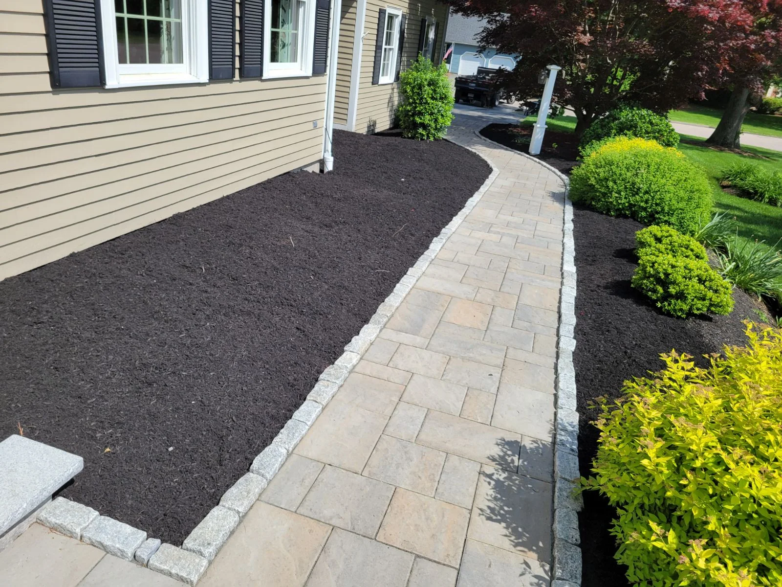 Paver entry walk curving between a home and planted border