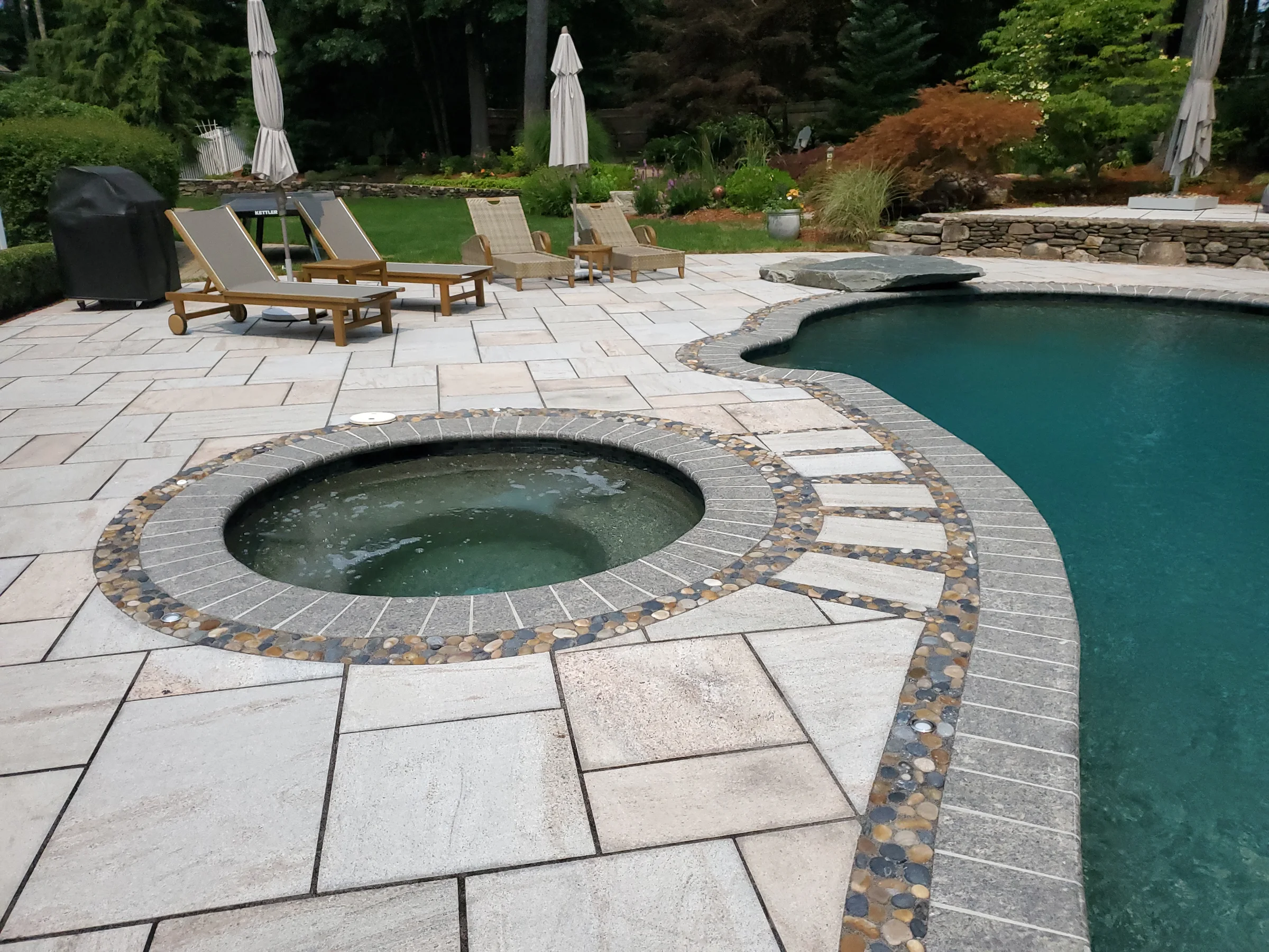 Curved pool and integrated circular spa edged in stone pavers
