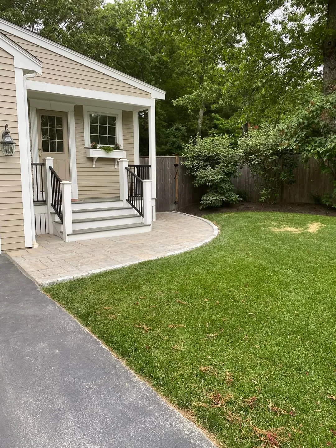 Rounded paver landing connecting a side entry to the lawn