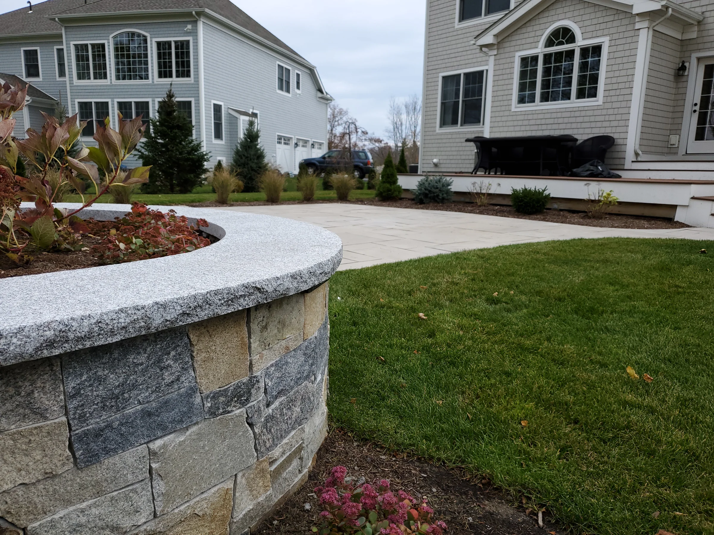 Curved stone seat wall enclosing a planted garden bed