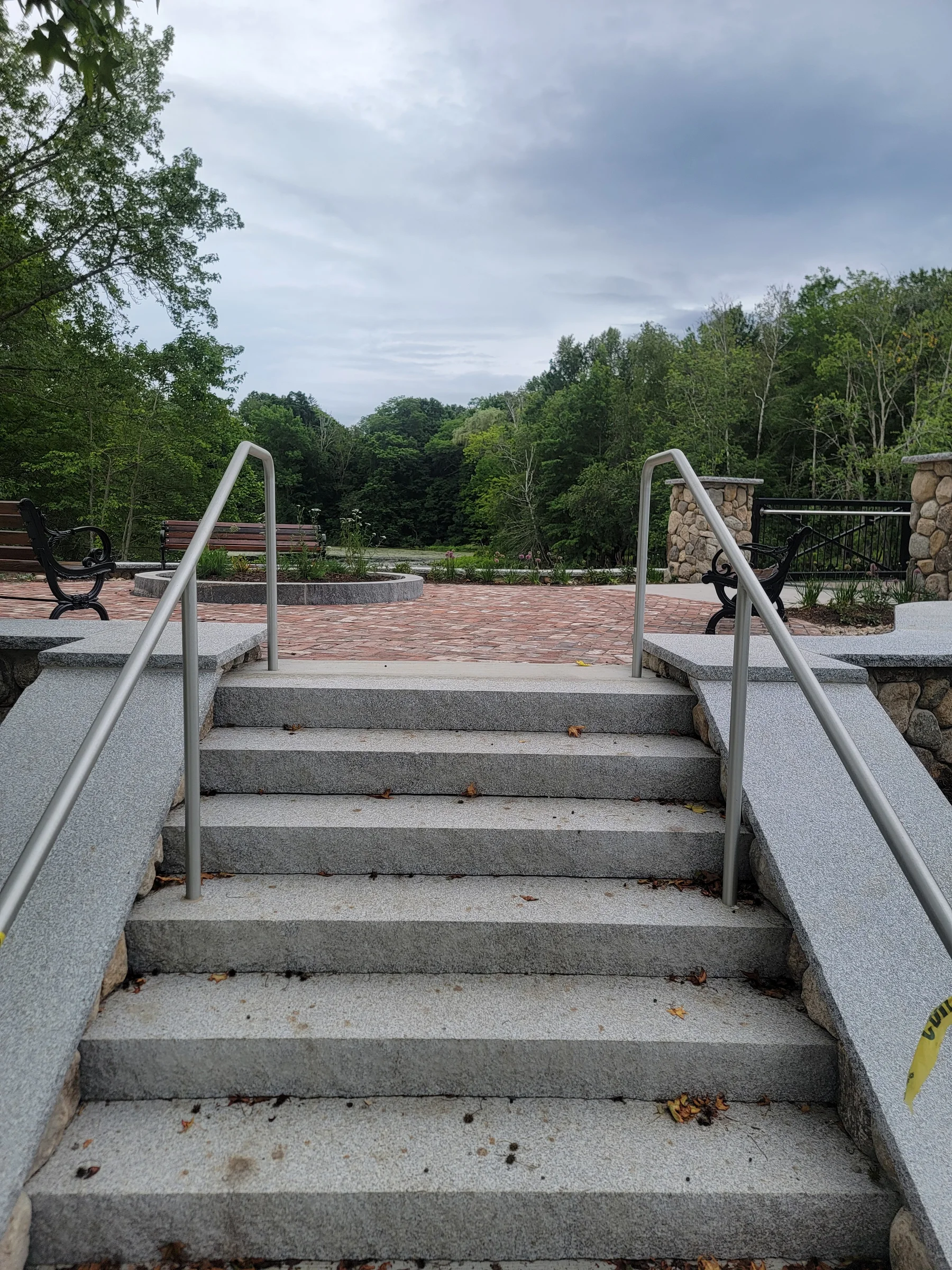 Broad concrete steps with metal handrails in a landscaped public space
