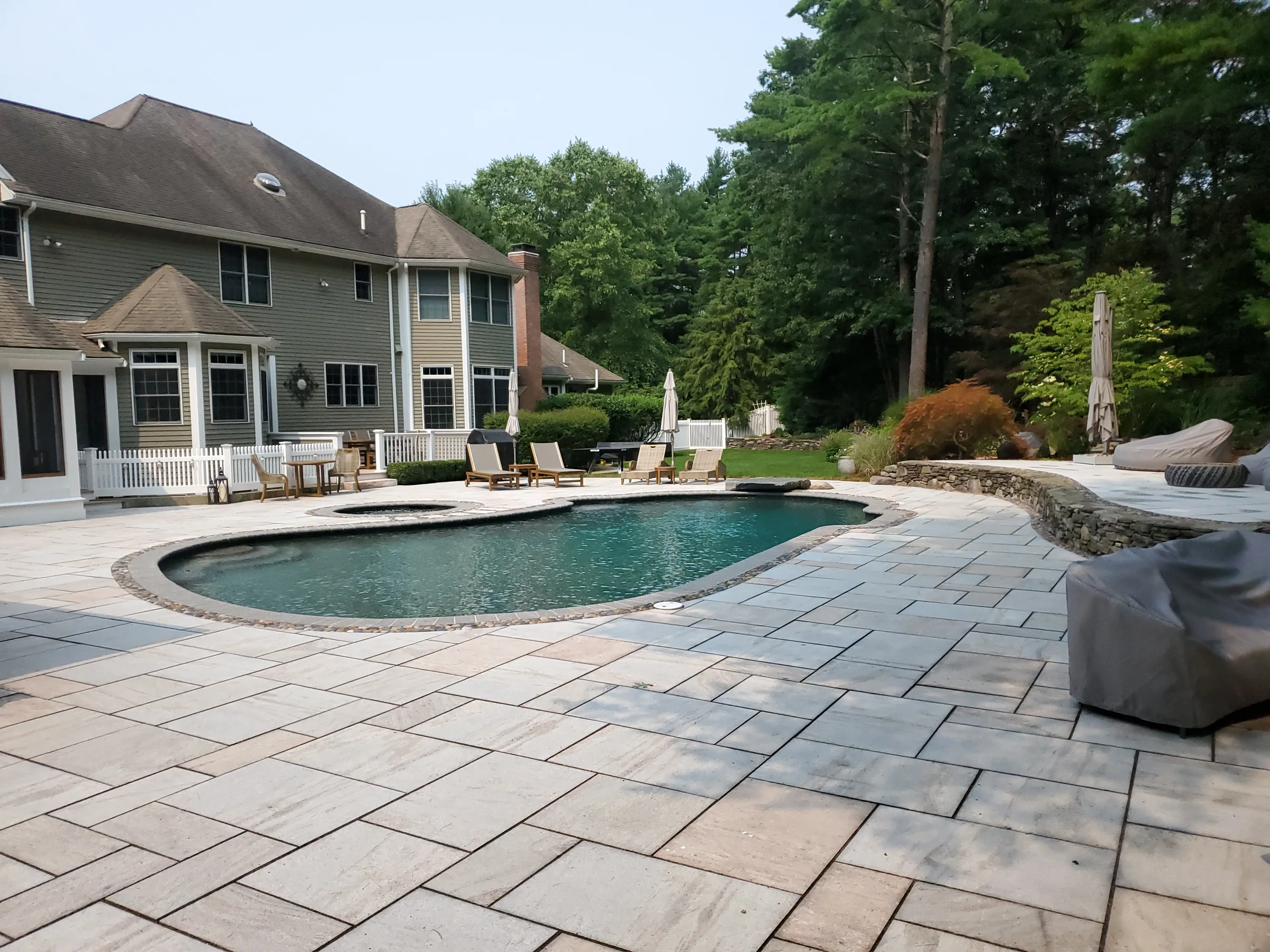 Finished backyard pool with a broad paver terrace