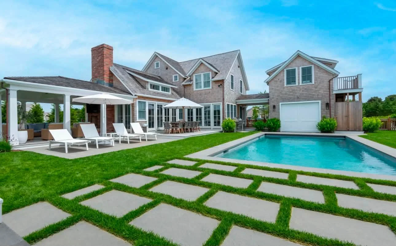 Contemporary coastal home with a rectangular pool and lawn-set pavers