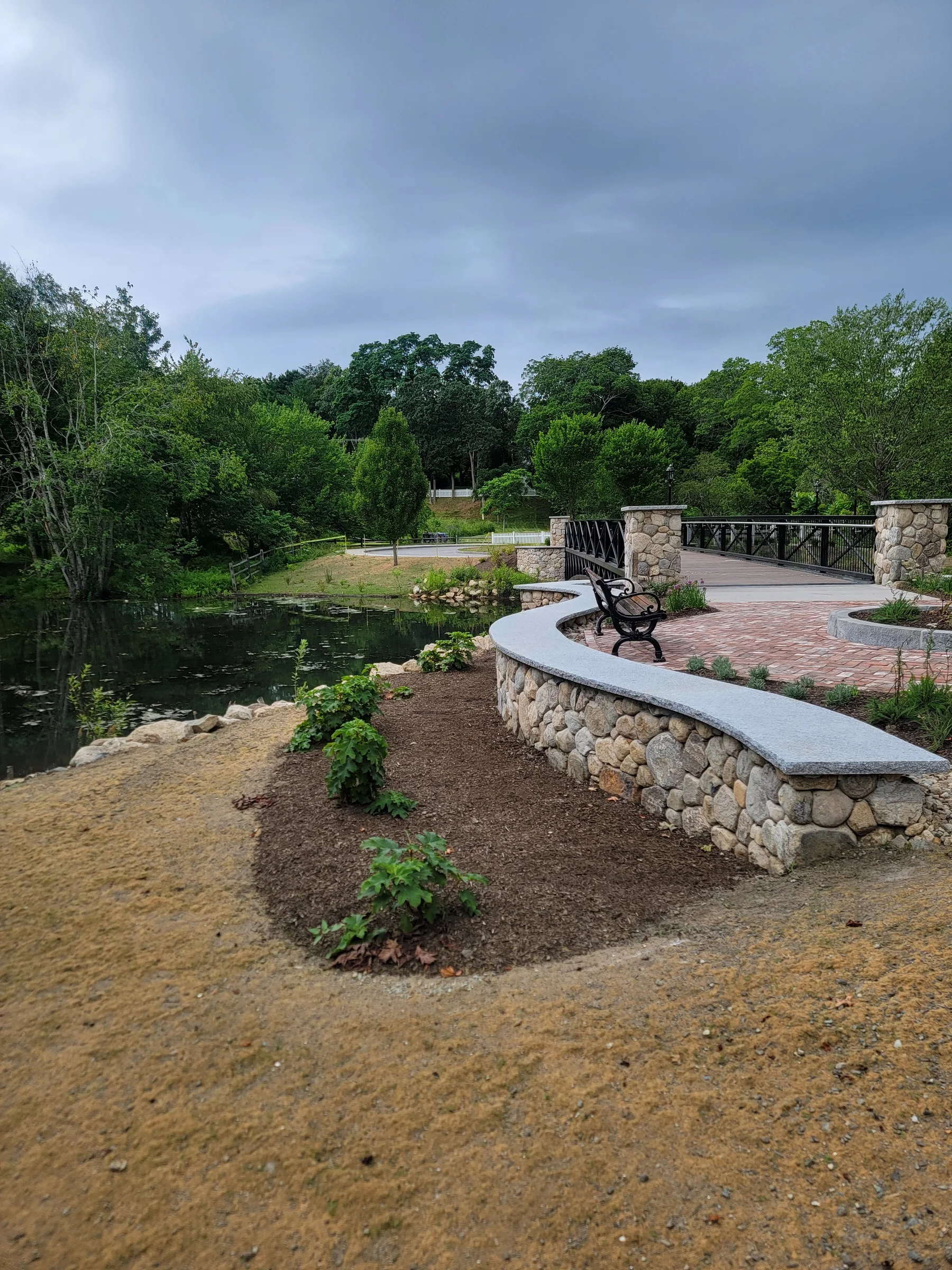 Curved stone wall and planting bed above a pond